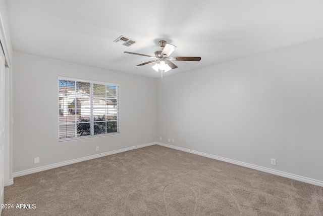 carpeted spare room featuring baseboards, visible vents, and a ceiling fan