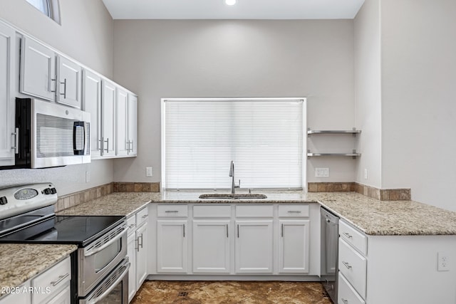 kitchen featuring light stone countertops, appliances with stainless steel finishes, white cabinets, and a sink