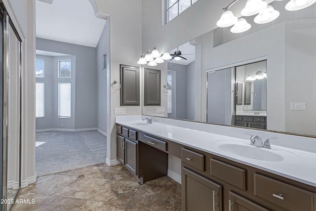 full bathroom featuring a sink, a towering ceiling, baseboards, and double vanity