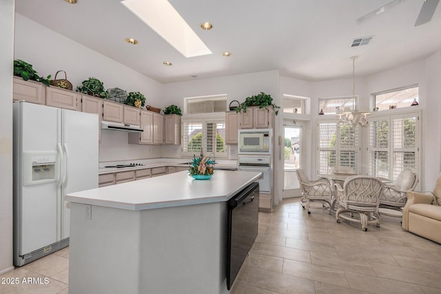 kitchen featuring a wealth of natural light, white appliances, a center island, and a skylight