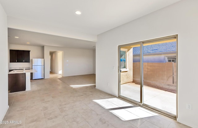 unfurnished living room with light tile patterned flooring, plenty of natural light, and sink