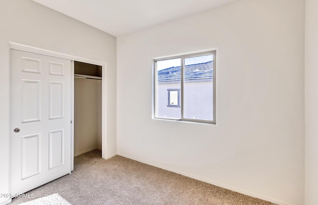 unfurnished bedroom featuring light colored carpet and a closet