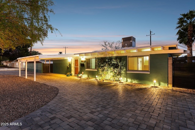 view of front of property featuring a carport, cooling unit, concrete block siding, and decorative driveway