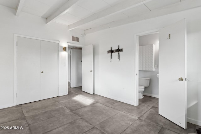 unfurnished bedroom featuring visible vents, connected bathroom, baseboards, beam ceiling, and a closet