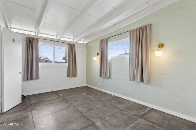 unfurnished room featuring vaulted ceiling with beams, baseboards, and a wealth of natural light