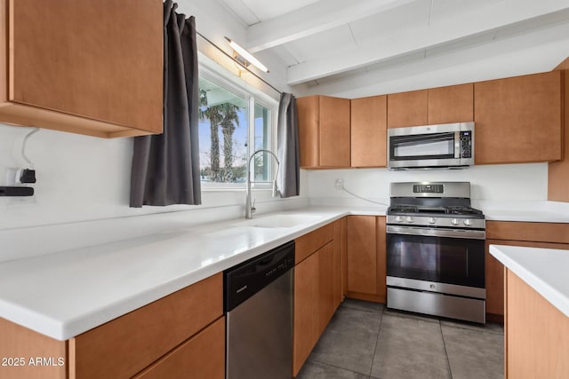 kitchen with light countertops, lofted ceiling with beams, light tile patterned floors, appliances with stainless steel finishes, and a sink