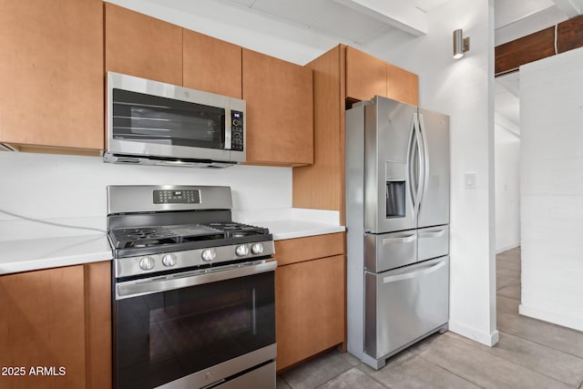 kitchen featuring appliances with stainless steel finishes, brown cabinetry, and light countertops