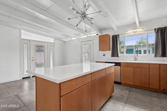 kitchen with a kitchen island, beamed ceiling, dishwasher, light countertops, and a sink