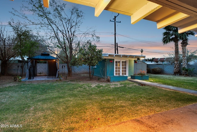 view of front facade with a gazebo, a front yard, an outbuilding, and a fenced backyard