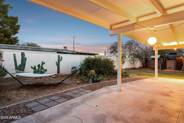 patio terrace at dusk with a gazebo and a fenced backyard