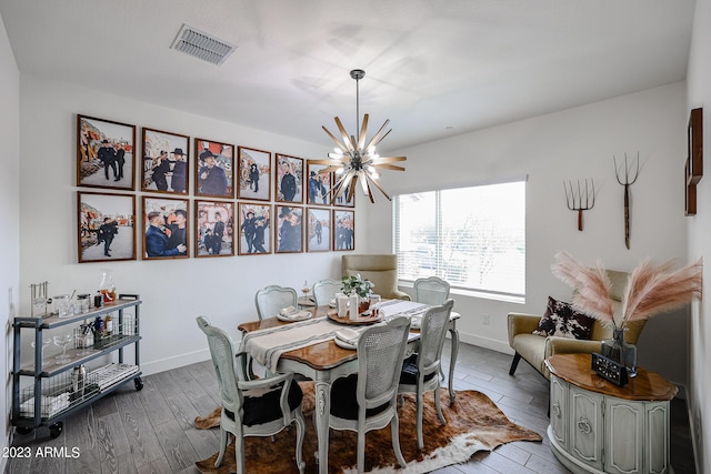 dining room featuring visible vents, baseboards, wood finished floors, and a notable chandelier