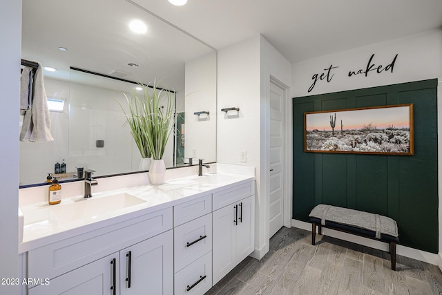 bathroom featuring double vanity, a sink, wood finished floors, and recessed lighting