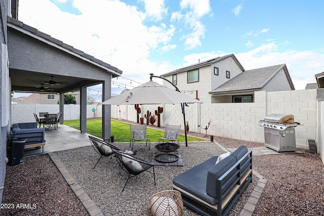 view of patio with area for grilling, a fire pit, a ceiling fan, and a fenced backyard