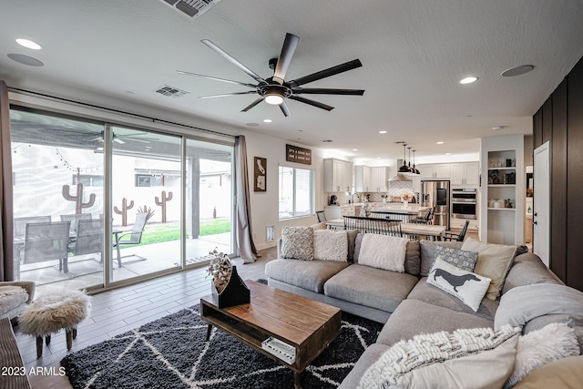 living area featuring ceiling fan, recessed lighting, and visible vents