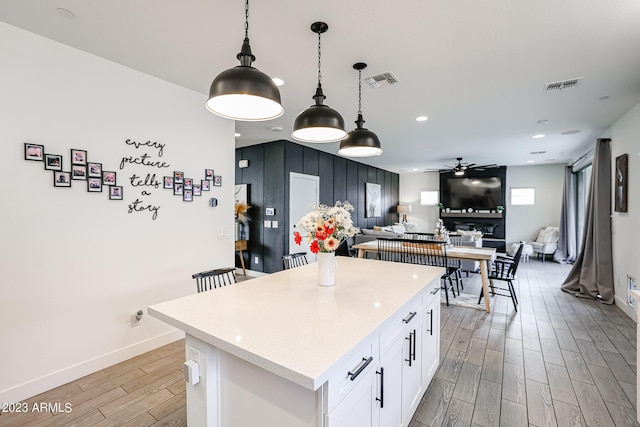 kitchen with white cabinets, wood finish floors, visible vents, and ceiling fan