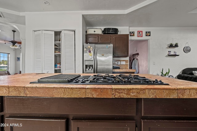 kitchen with black gas cooktop, ceiling fan, dark brown cabinets, and stainless steel refrigerator with ice dispenser