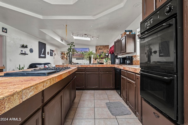 kitchen featuring light tile patterned floors, track lighting, black appliances, a raised ceiling, and dark brown cabinetry