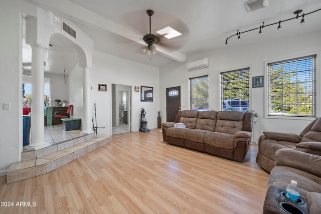 living room with light hardwood / wood-style flooring, a wall mounted AC, ceiling fan, and ornate columns