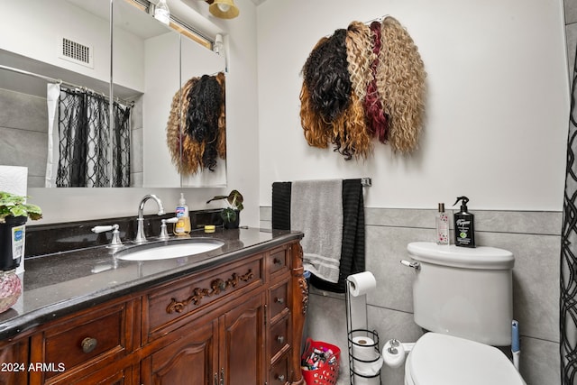 bathroom featuring curtained shower, tile walls, toilet, and vanity