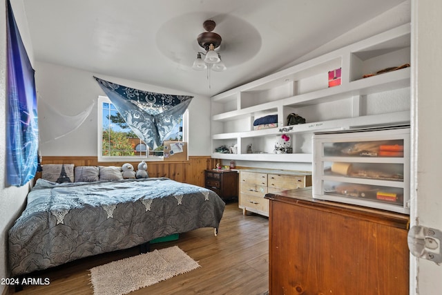 bedroom with ceiling fan, wooden walls, and dark hardwood / wood-style floors