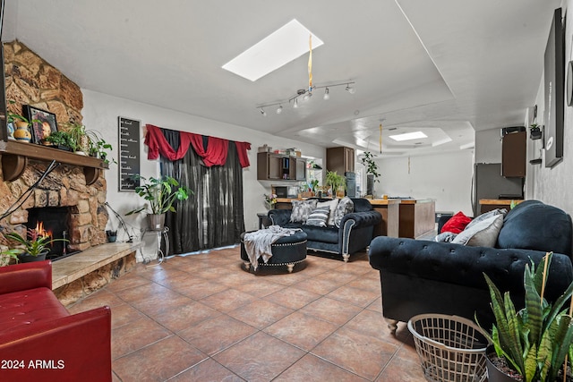 tiled living room with a fireplace, a tray ceiling, and a skylight