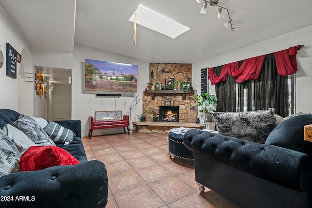 tiled living room with a skylight and a stone fireplace