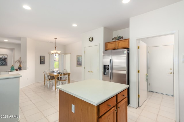 kitchen featuring a kitchen island, stainless steel refrigerator with ice dispenser, light tile patterned flooring, decorative light fixtures, and a chandelier