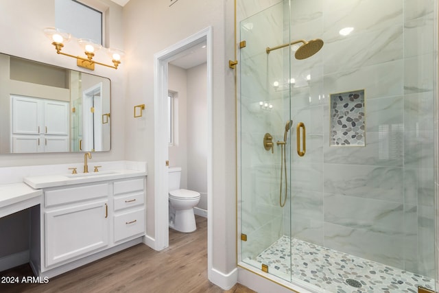 bathroom with vanity, hardwood / wood-style floors, a shower with shower door, and toilet