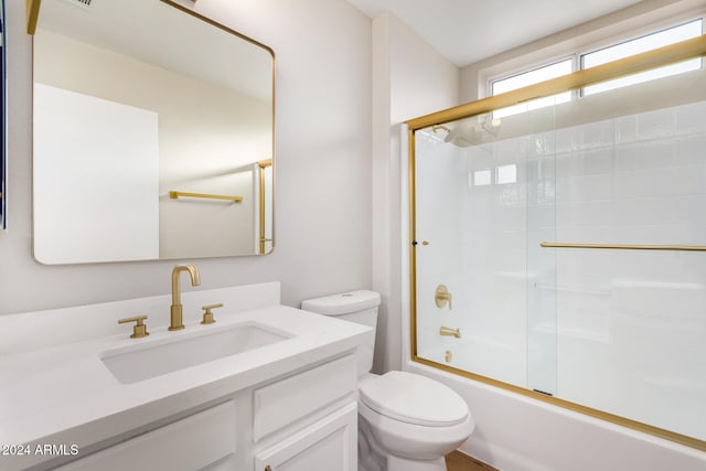 full bathroom with vanity, bath / shower combo with glass door, and toilet