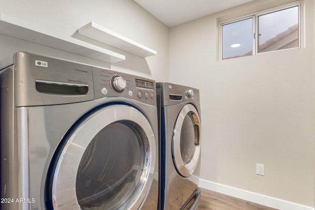 laundry room with washer and clothes dryer and light wood-type flooring