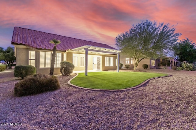 back house at dusk featuring a yard, a patio, and a pergola