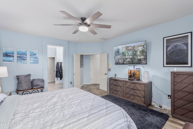 bedroom with a walk in closet, ceiling fan, a closet, and wood-type flooring