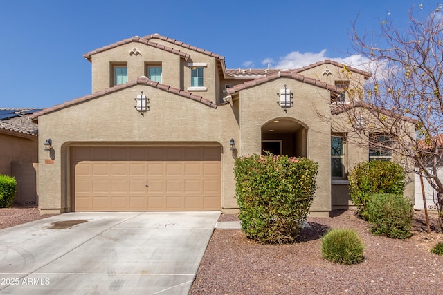 mediterranean / spanish-style house with an attached garage, a tile roof, concrete driveway, and stucco siding