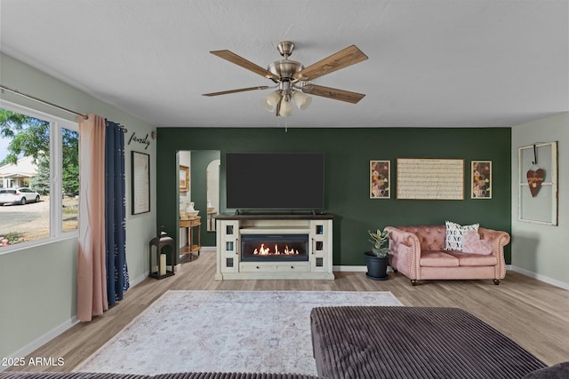 6289 E Duchess Dr, Prescott Valley, AZ 86314 - living room with wood finished floors, a ceiling fan, a warm lit fireplace, and baseboards