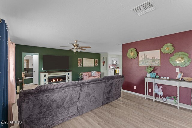 6289 E Duchess Dr, Prescott Valley, AZ 86314 - living area with wood finished floors, a ceiling fan, a lit fireplace, arched walkways, and baseboards