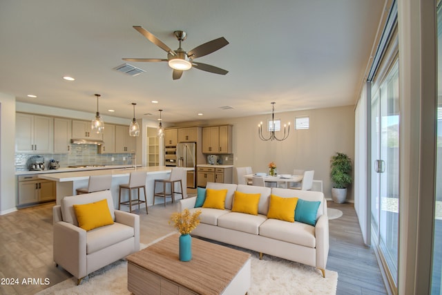 living room featuring sink, light hardwood / wood-style flooring, and ceiling fan with notable chandelier