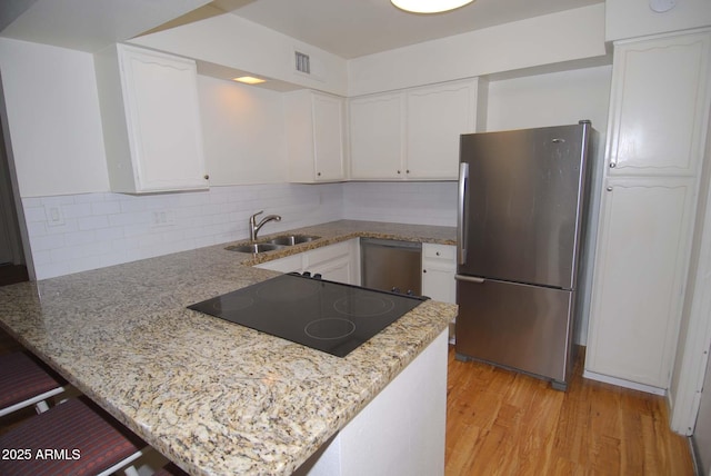 2015 E Southern Ave Unit 23, Tempe, AZ 85282 - kitchen with freestanding refrigerator, black electric cooktop, a peninsula, light wood-style floors, and white cabinetry