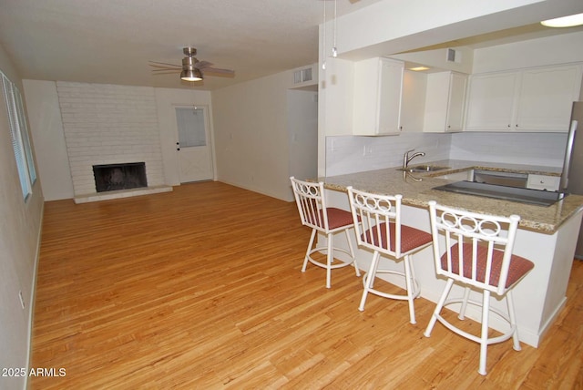 2015 E Southern Ave Unit 23, Tempe, AZ 85282 - kitchen featuring ceiling fan, light wood finished floors, white cabinets, and a kitchen breakfast bar