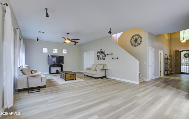 living area with a barn door, baseboards, visible vents, light wood-style floors, and a ceiling fan