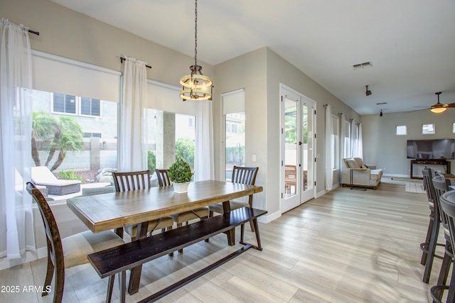 dining space featuring french doors, light wood-type flooring, baseboards, visible vents, and ceiling fan with notable chandelier