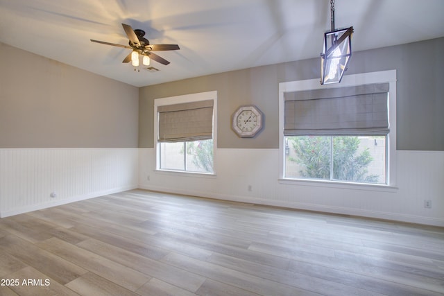 unfurnished room featuring ceiling fan, a wainscoted wall, and wood finished floors
