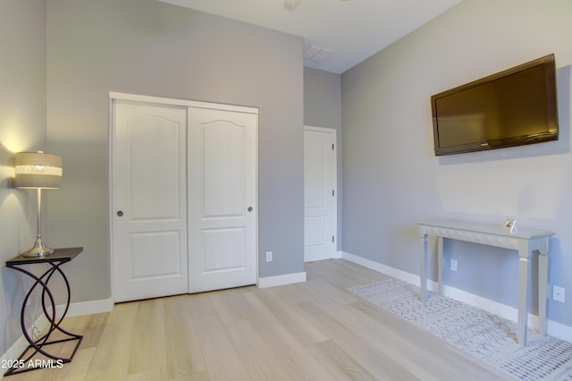unfurnished bedroom with baseboards, wood finished floors, and a closet