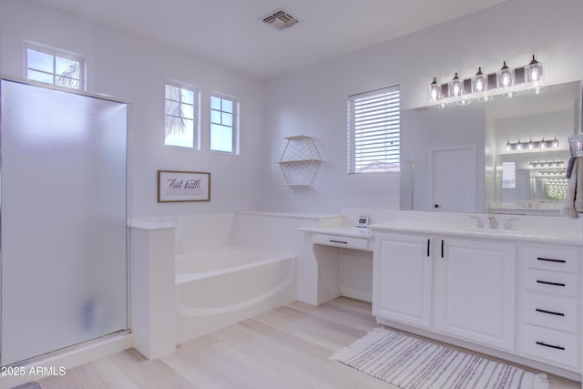 bathroom featuring a garden tub, wood finished floors, visible vents, and a stall shower
