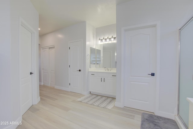 bathroom featuring a shower with shower door, baseboards, recessed lighting, wood finished floors, and vanity