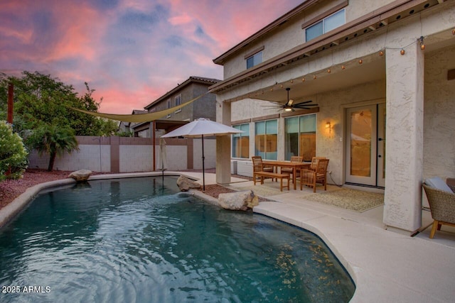 pool at dusk featuring a fenced backyard, a patio area, a ceiling fan, and a fenced in pool