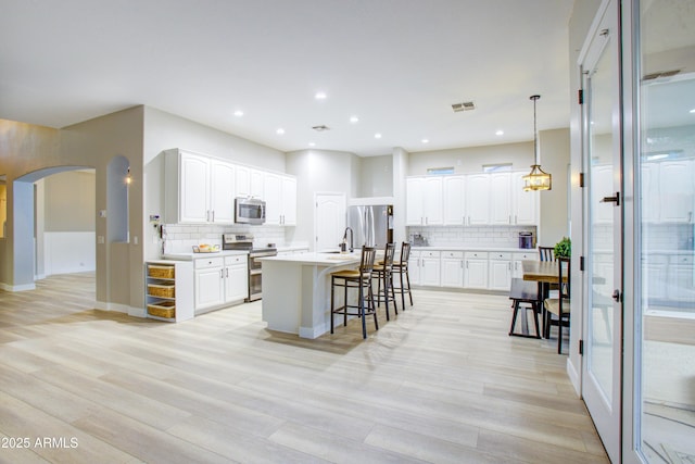 kitchen featuring decorative backsplash, stainless steel appliances, visible vents, and arched walkways