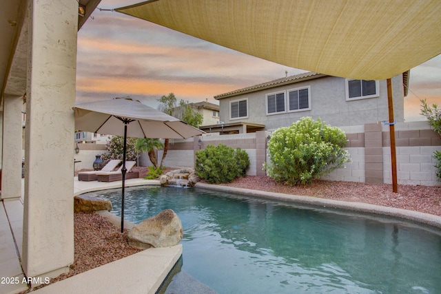 pool at dusk featuring a fenced backyard and a fenced in pool