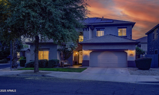 traditional home with a garage, solar panels, concrete driveway, and stucco siding
