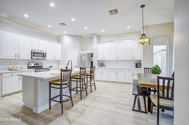 kitchen featuring light countertops, tasteful backsplash, visible vents, and appliances with stainless steel finishes
