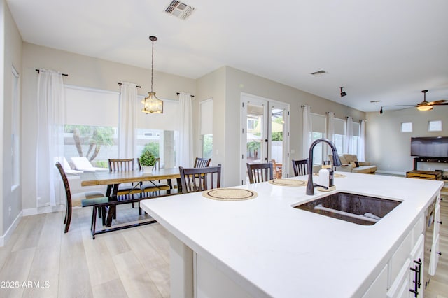 kitchen with light countertops, visible vents, ceiling fan, and a sink